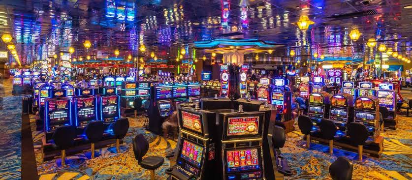 Panor&aacute;mica de una sala de juegos con filas de tragamonedas encendidas
